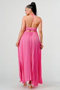 Backless tie-around detail adds allure and sophistication Rêve Dorés Model wearing a flowing pink halter-neck maxi dress with a ruched bodice and pleated skirt. The elegant, airy design creates a graceful silhouette, perfect for formal events, summer gatherings, or beach weddings. Stretchable fabric with elastic back ensures a comfortable and flexible fit