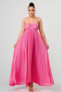 Model wearing a flowing pink halter-neck maxi dress with a ruched bodice and pleated skirt. The elegant, airy design creates a graceful silhouette, perfect for formal events, summer gatherings, or beach weddings -  Rêve Dorés