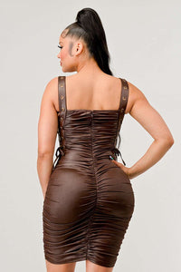 Shirring Detail PU Mini Dress - Model wearing a sleek brown ruched mini dress featuring adjustable straps with buckle details and side ties. The form-fitting silhouette and leather-like texture create a bold and edgy look, perfect for a night out or statement-making occasions. Rêve Dorés