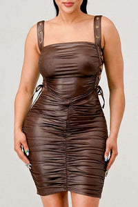 Shirring Detail PU Mini Dress - Model wearing a sleek brown ruched mini dress featuring adjustable straps with buckle details and side ties. The form-fitting silhouette and leather-like texture create a bold and edgy look, perfect for a night out or statement-making occasions. Rêve Dorés