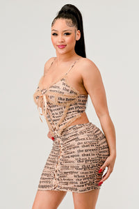 NEWSLETTER PRINT SEXY MINI DRESS
Model wearing a beige mini dress with a newspaper print, drawstring waist, and spaghetti straps. - Rêve Dorés