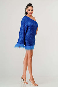 Model wearing a dazzling one-shoulder mini dress in vibrant blue, covered in shimmering sequins and featuring a dramatic single sleeve. The hem and sleeve are accented with matching feathered trim, creating a bold and luxurious look ideal for parties and special occasions - Rêve Dorés