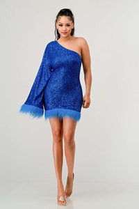 Model wearing a dazzling one-shoulder mini dress in vibrant blue, covered in shimmering sequins and featuring a dramatic single sleeve. The hem and sleeve are accented with matching feathered trim, creating a bold and luxurious look ideal for parties and special occasions - Rêve Dorés