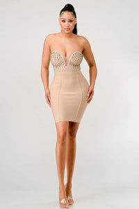 Woman in a beige bandage dress with a plunging embellished sweetheart neckline and figure-hugging silhouette