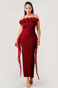 off-shoulder red midi dress with an intricate lace pattern and a decorative row of roses along the neckline. Ethereal tulle streamers flow from the waist, and the look is completed with transparent high-heeled sandals. Rêve Dorés