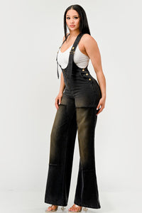 Urban Noir Denim Overalls Black Jumpsuit. Rêve Dorés Model wearing a stylish black denim overall jumpsuit featuring wide-leg pants, adjustable straps, and a front zipper closure. Paired with a white fitted tank top, this outfit offers a chic and modern twist on classic overalls, perfect for casual yet trendy looks.