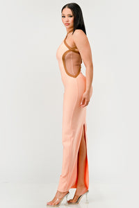 Peaches and Cream Infinity Gown Bandage dress Model wearing a sleek peach maxi dress featuring a halter neckline with contrasting brown trim accents that outline the curves, creating a sophisticated and contemporary silhouette. Perfect for formal events or evening occasions - Rêves Dorés