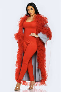 A model showcases a red jumpsuit paired with azure blue tulle sleeves and red feather details.