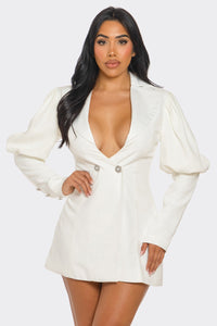 Model wearing a chic white blazer-style mini dress featuring a deep V-neckline, structured shoulders, puffed long sleeves, and decorative rhinestone buttons for a sophisticated and elegant look - Rêve Dorés